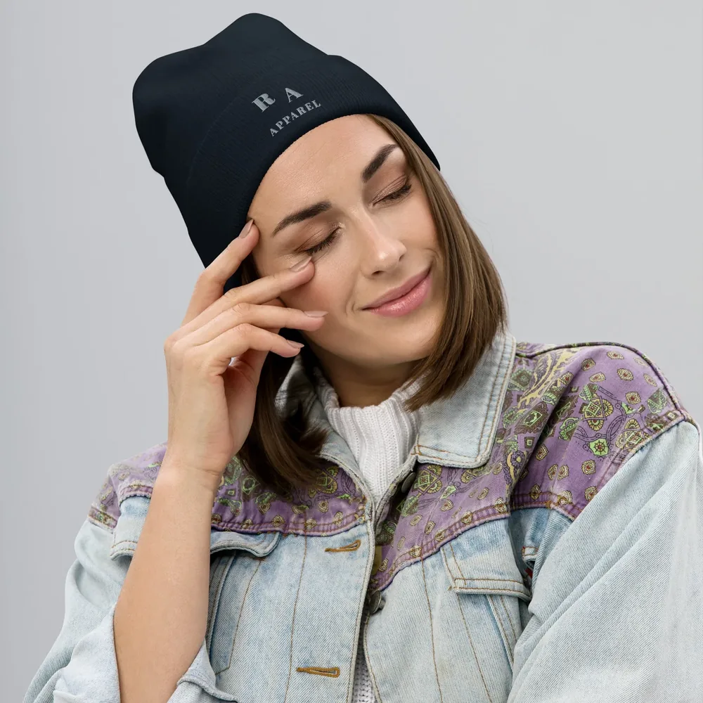 A woman wears the black Timeless Beanie, embroidered R A Apparel, with a soft denim jacket.